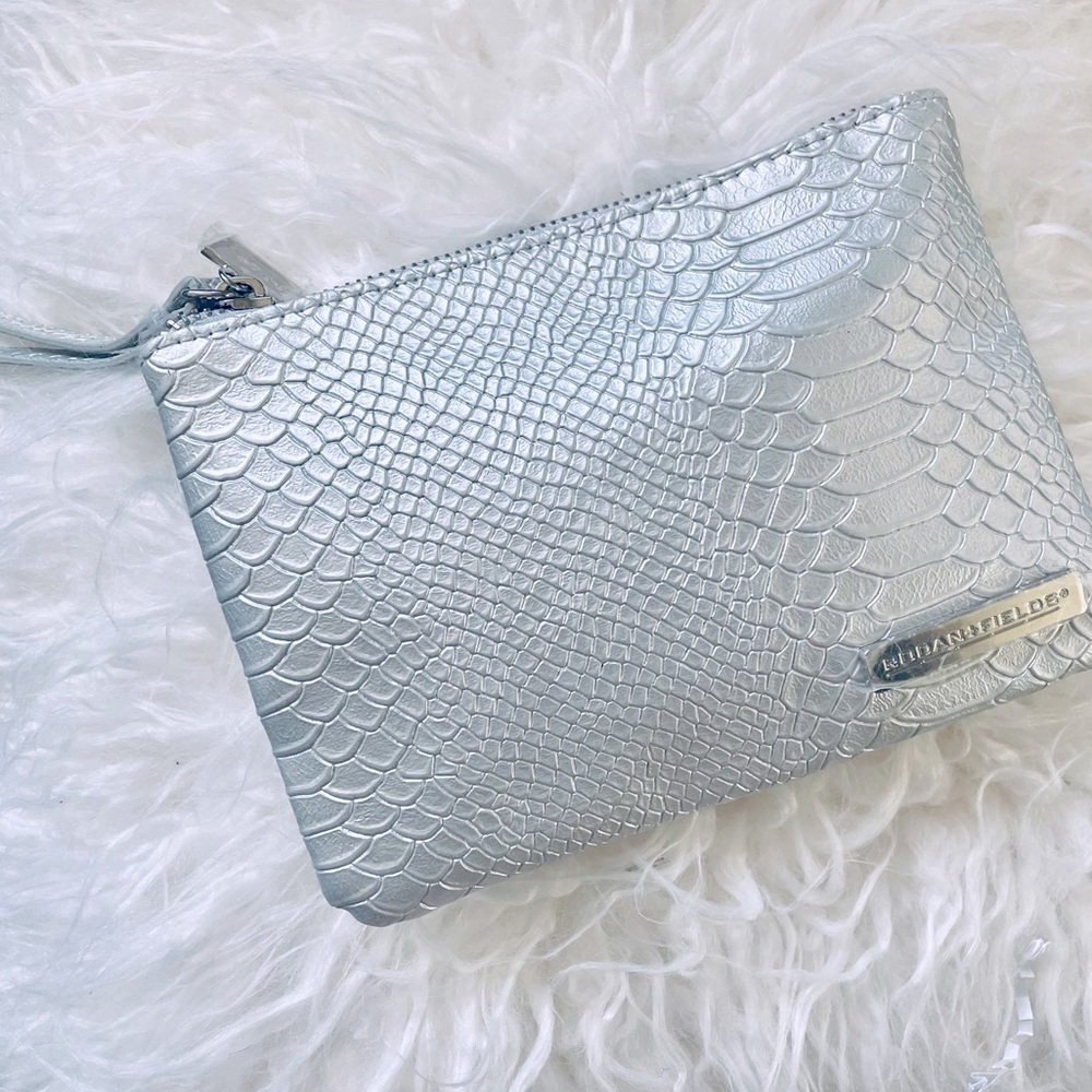 Brand new textured silver wristlet with Rodan + Fields products inside.